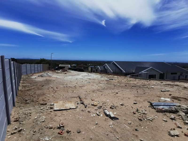 A vacant residential plot featuring a precast concrete boundary wall and views of the surrounding neighborhood.