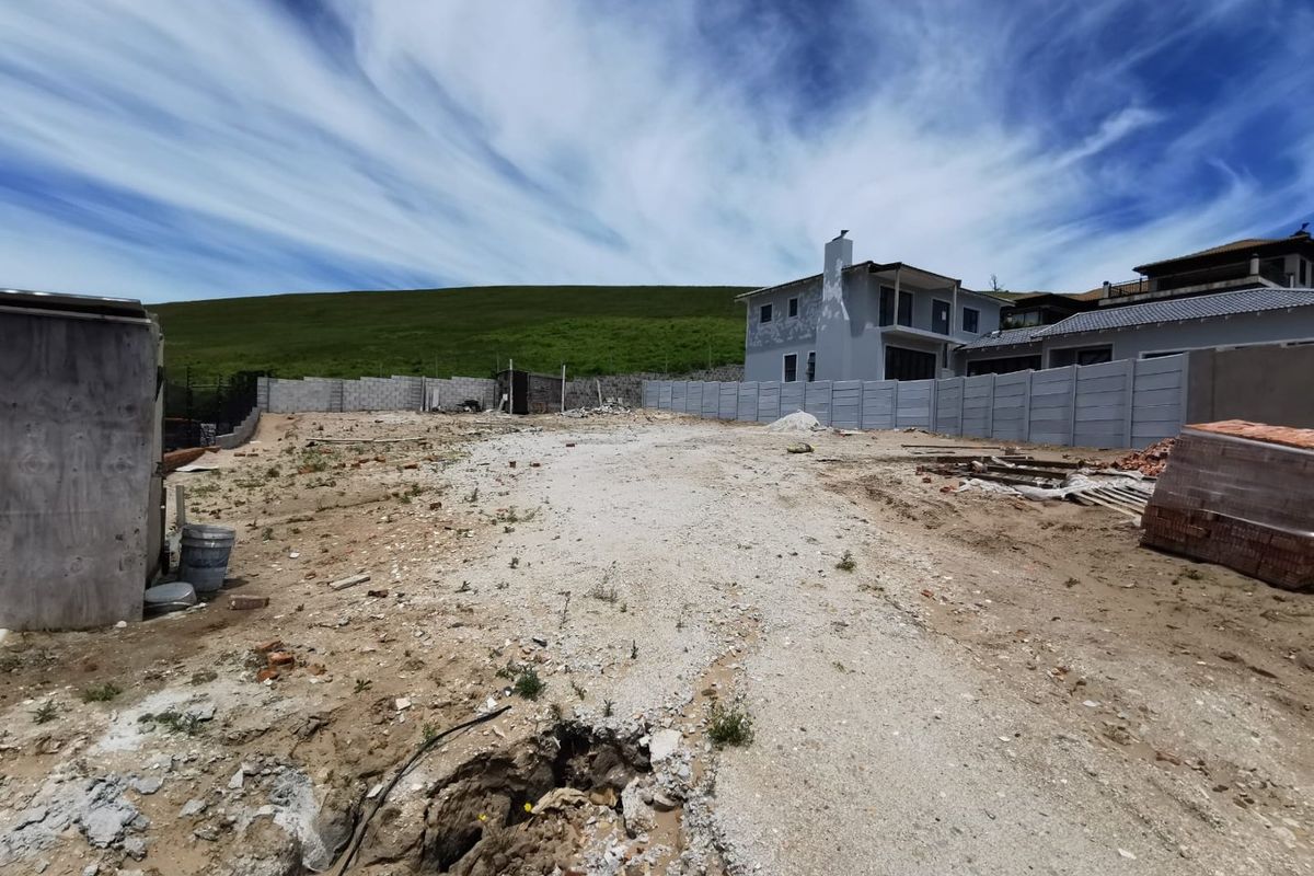 A vacant residential plot featuring a precast concrete boundary wall and gravel ground surface, ready for development.