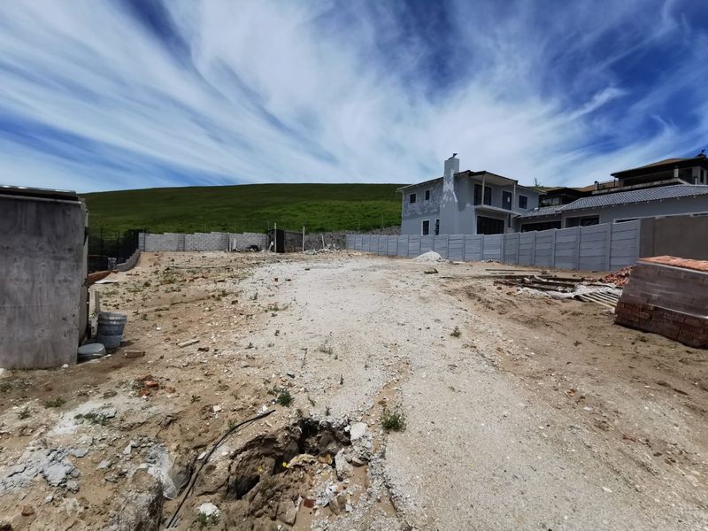 A vacant residential plot featuring a precast concrete boundary wall and gravel ground surface, ready for development.