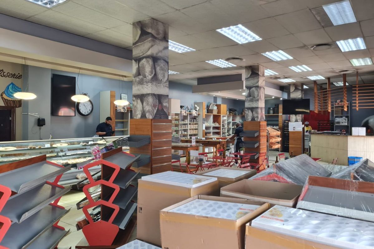 Spacious commercial retail area featuring a service counter, built-in display shelving, and suspended ceiling with recessed lighting, suitable for a bakery or cafe setup.