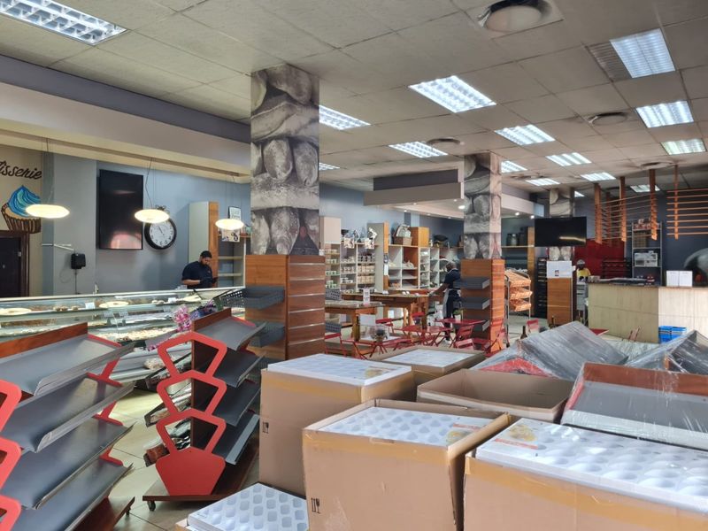 Spacious commercial retail area featuring a service counter, built-in display shelving, and suspended ceiling with recessed lighting, suitable for a bakery or cafe setup.