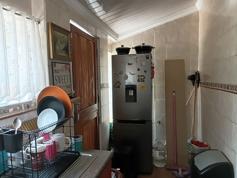A functional scullery area featuring tiled walls, a stainless steel sink, and a timber door, providing practical utility space for the home.