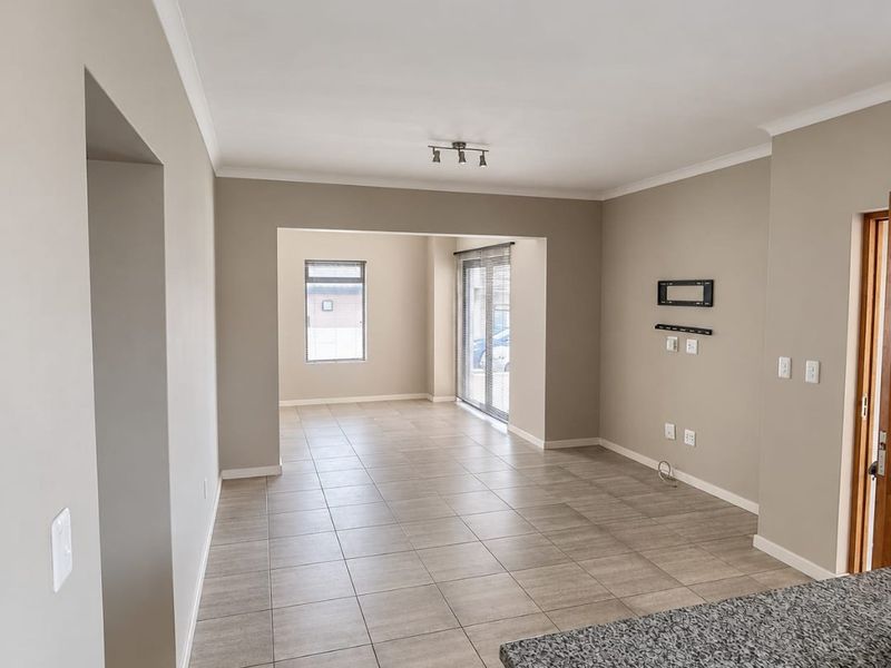 Spacious open-plan living area featuring neutral wall tones, tiled flooring, and direct access to the exterior through sliding glass doors.