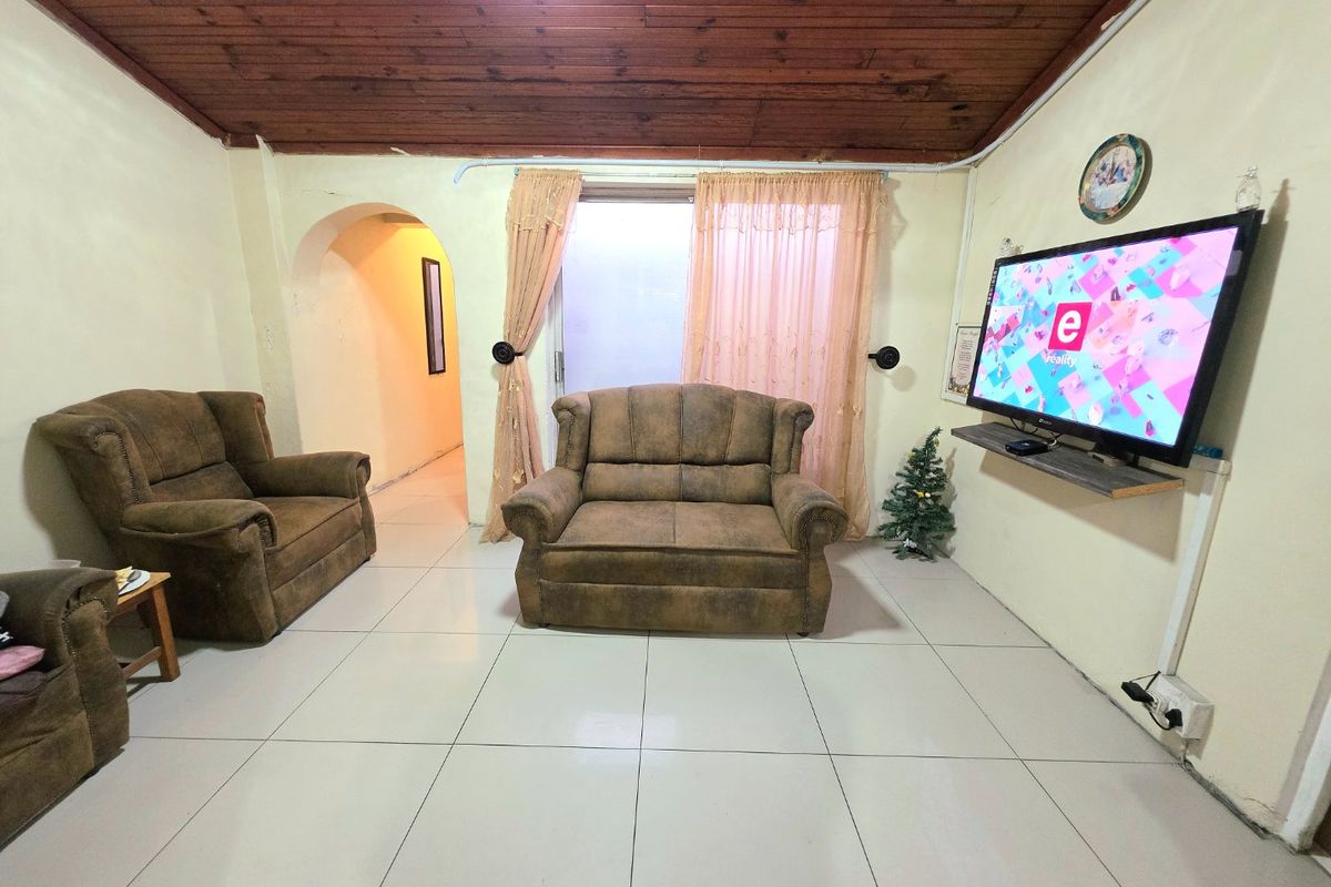 Living room featuring ceramic floor tiles, a timber tongue and groove ceiling, and an arched doorway leading to an adjacent space.