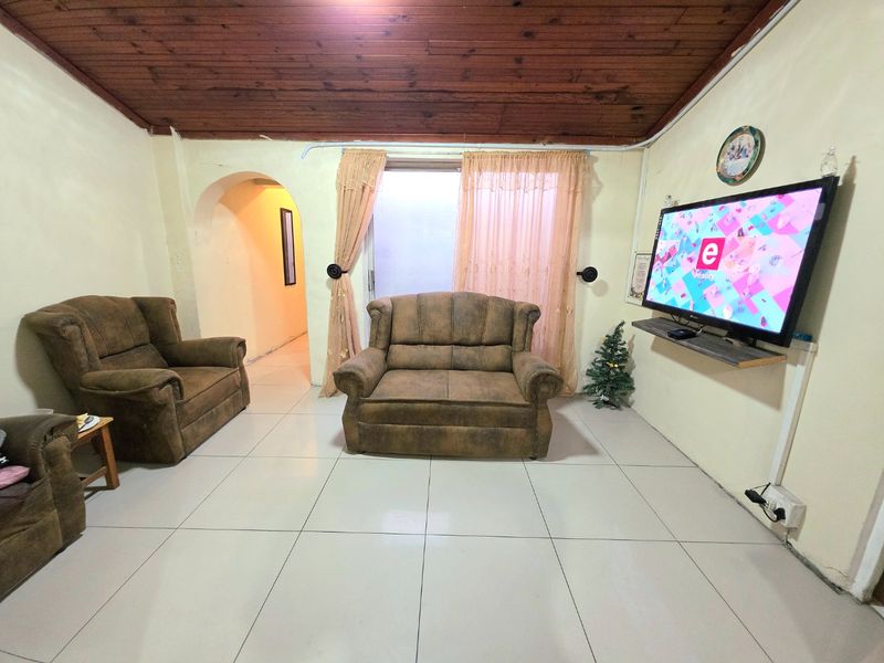 Living room featuring ceramic floor tiles, a timber tongue and groove ceiling, and an arched doorway leading to an adjacent space.