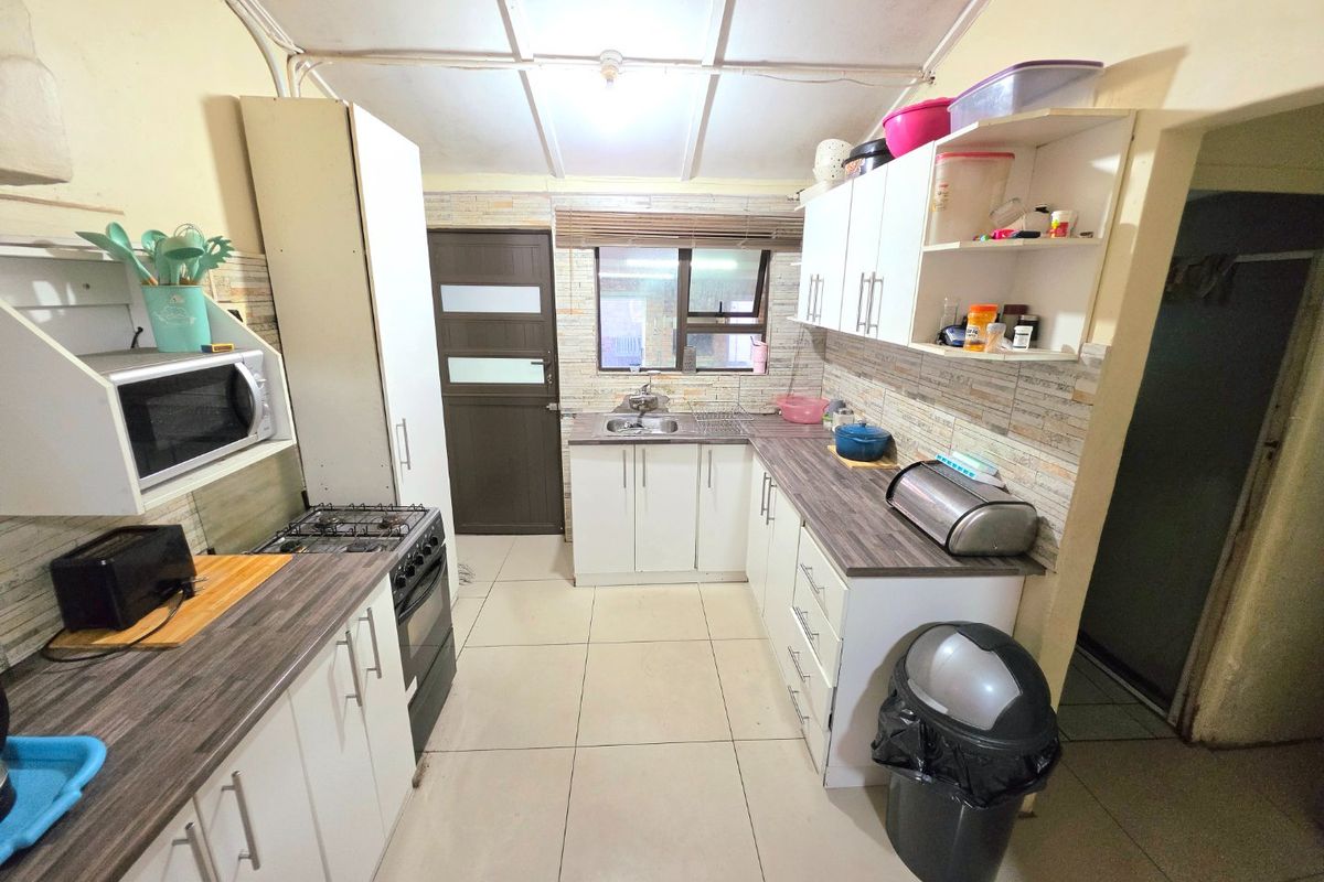 Functional kitchen featuring white cabinetry, laminate countertops, tiled backsplash, and gas stove, with direct access to an exterior door.