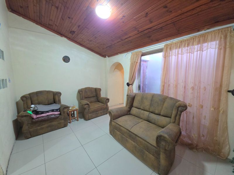 Living room featuring a timber tongue and groove ceiling, ceramic tiled flooring, and a sliding glass door leading to an outdoor area.