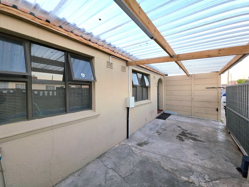 A covered outdoor patio area featuring a corrugated roof, concrete flooring, and direct access to the home's exterior.