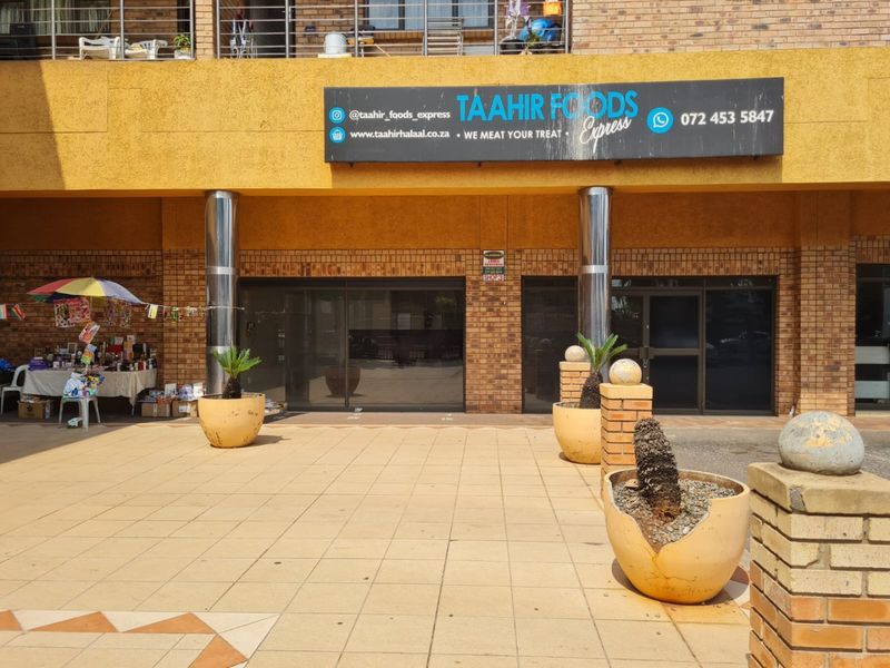 Commercial storefront entrance featuring brick facade, metal columns, and tiled exterior area with prominent business signage.