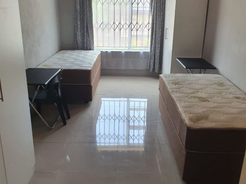 A functional bedroom featuring tiled flooring, security bars on the window, and a timber ceiling.