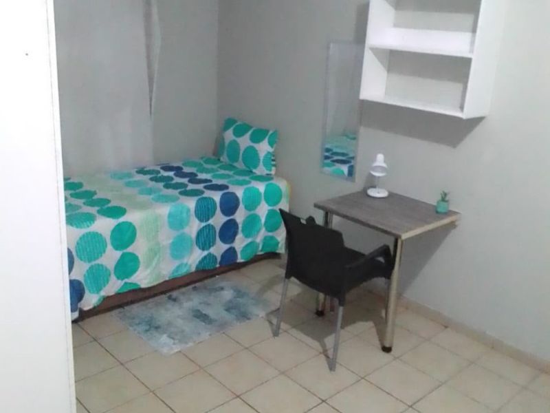 A compact bedroom featuring tiled flooring and wall-mounted shelving.