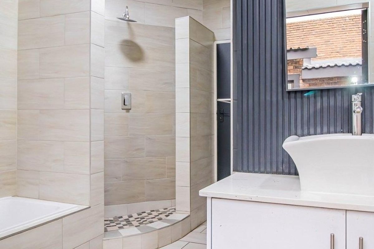 Modern bathroom featuring a walk-in shower with rain shower head, built-in vanity with vessel sink, and tiled finishes throughout.