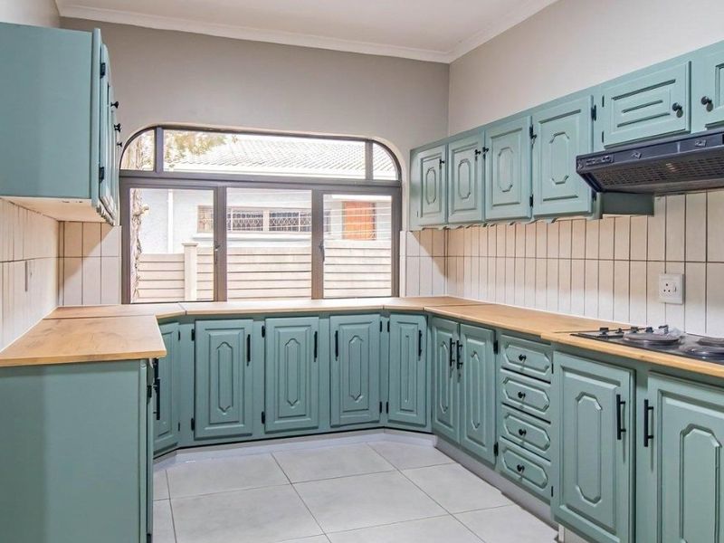 A functional kitchen featuring painted cabinetry, wooden countertops, tiled backsplash, and a built-in gas hob with an extractor fan.