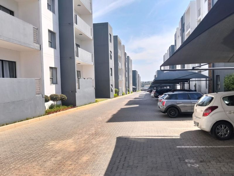 Exterior view of a modern apartment complex featuring paved driveways and designated covered parking bays for residents.