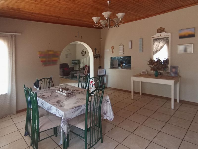Dining room featuring tiled flooring, a timber ceiling, and an arched opening leading to an adjacent living area.