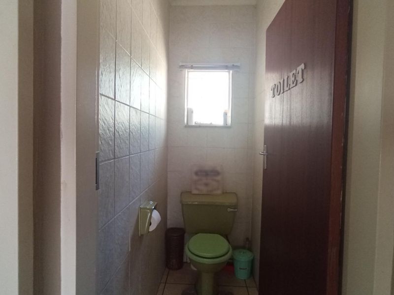 A small, functional guest toilet featuring dated green sanitaryware and tiled wall finishes.