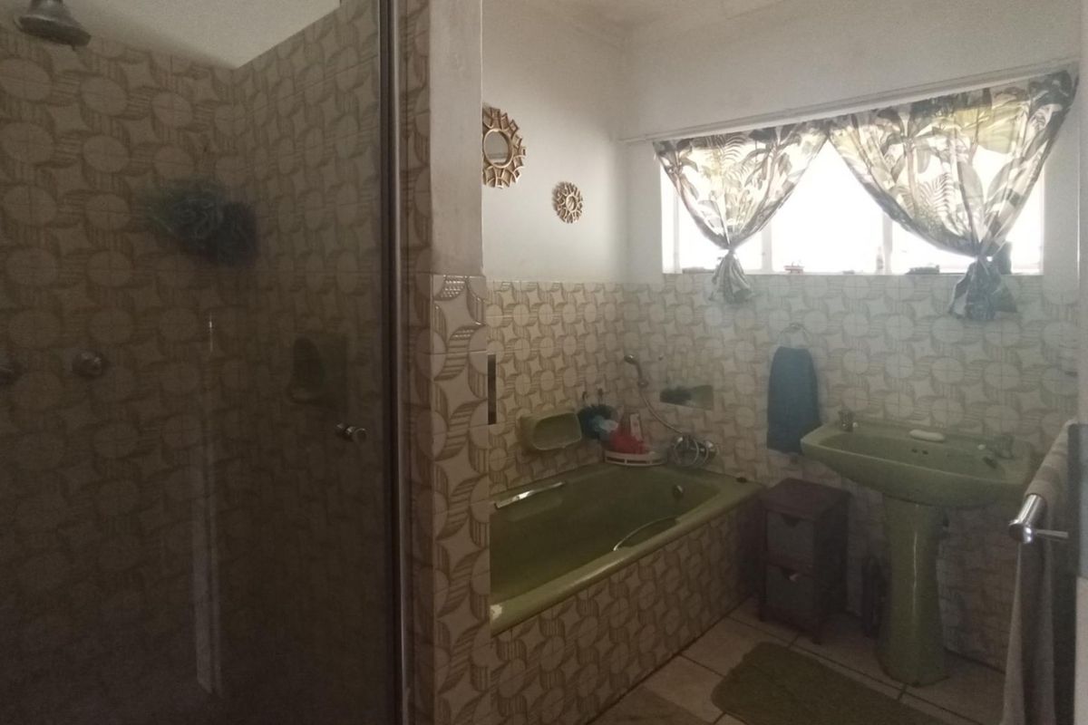 A dated bathroom featuring a built-in bathtub, pedestal basin, and separate shower enclosure with patterned wall tiling.
