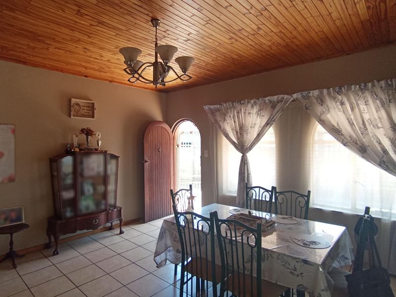 Dining room featuring a warm timber tongue and groove ceiling, ceramic tiled flooring, and an arched doorway leading to an adjacent space.