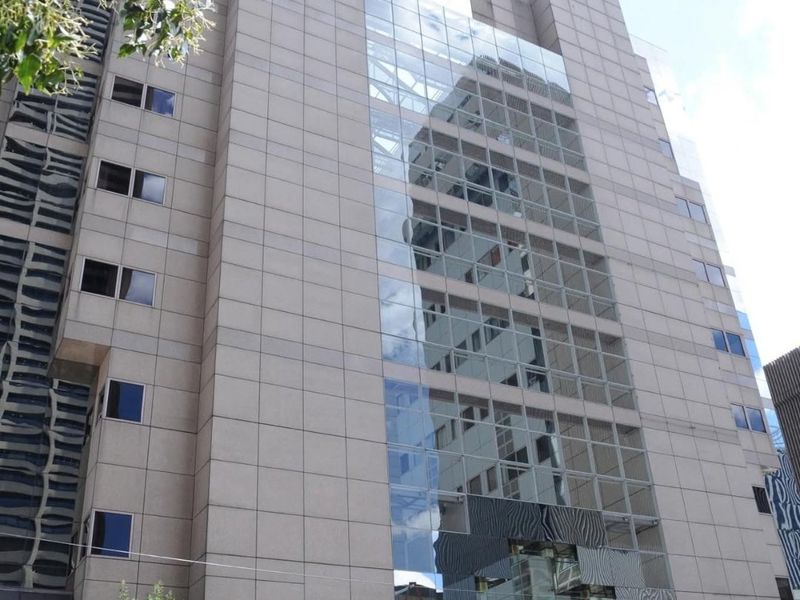 A modern multi-story apartment building facade featuring stone cladding and a prominent glass curtain wall design.