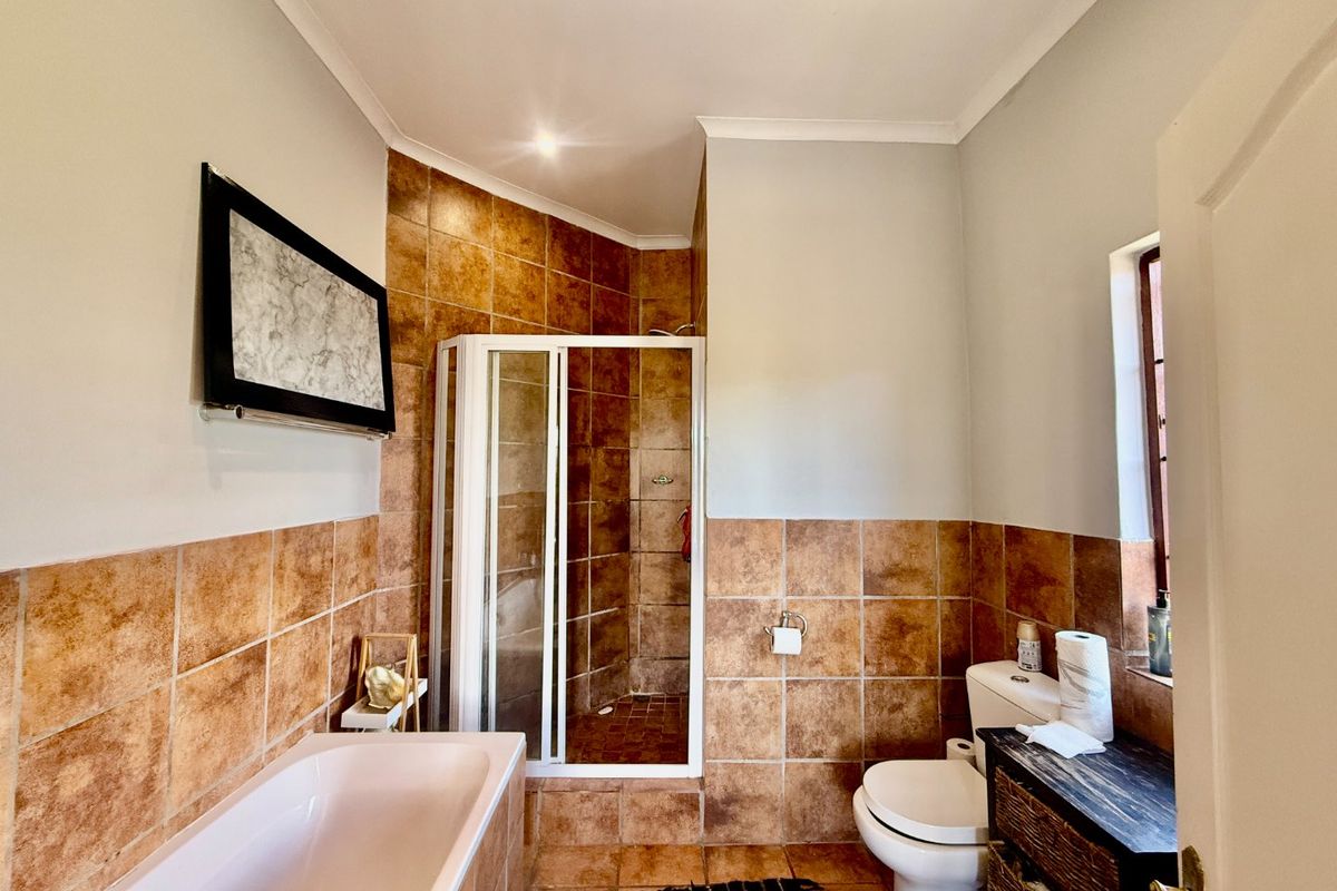 A functional bathroom featuring a built-in bathtub, a separate shower enclosure, and tiled finishes throughout.
