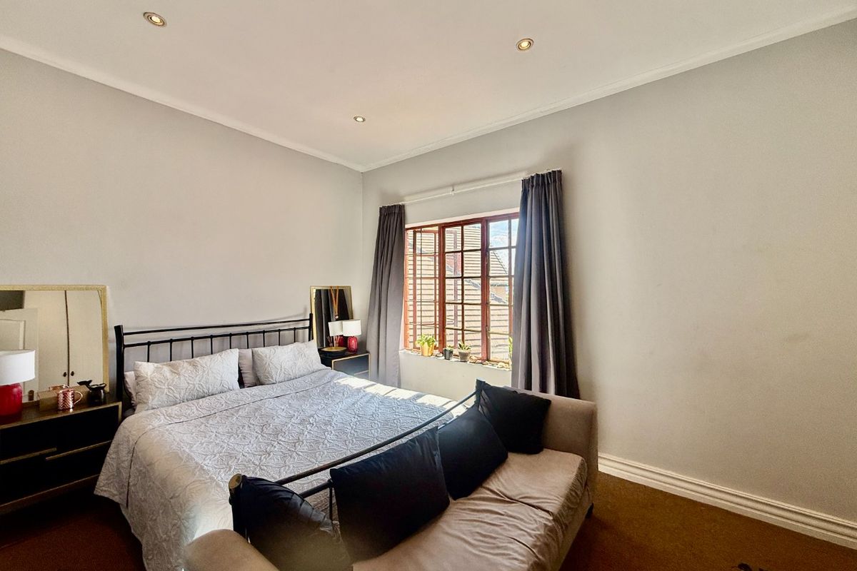 A bedroom featuring recessed downlights, timber-framed windows, and neutral wall finishes, providing a functional and well-lit sleeping space.