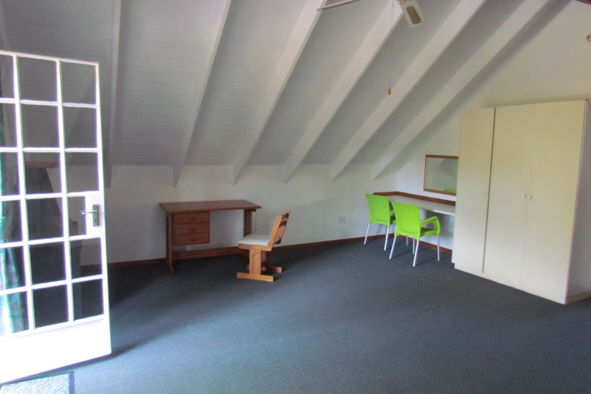 Spacious bedroom featuring a vaulted ceiling with exposed rafters, a built-in wardrobe, and a glass-paneled french door leading to the exterior.