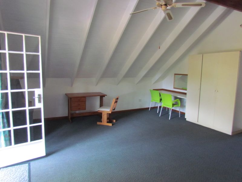 Spacious bedroom featuring a vaulted ceiling with exposed rafters, a built-in wardrobe, and a glass-paneled french door leading to the exterior.