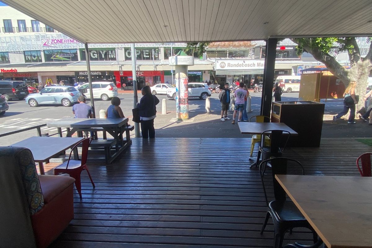 Covered outdoor timber deck area providing street-level seating with views of the surrounding commercial precinct.