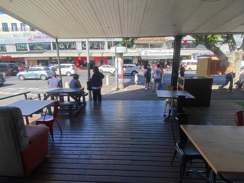 Covered outdoor timber deck area providing street-level seating with views of the surrounding commercial precinct.