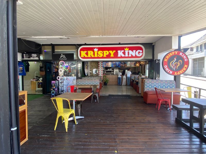 A commercial outdoor patio area featuring timber decking and covered ceiling, serving as an entrance to a retail and food service establishment.