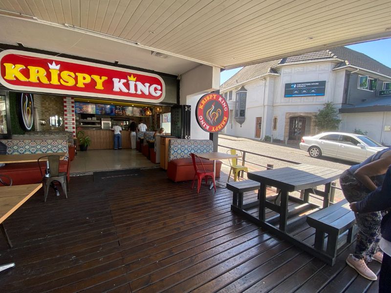 A covered outdoor patio area featuring timber decking, integrated commercial signage, and bi-fold doors leading into the main restaurant space.