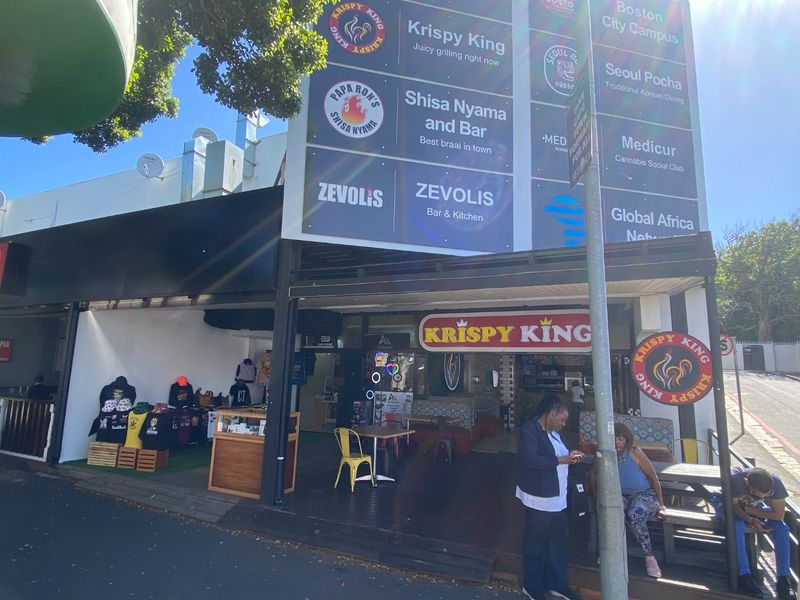 Front facade of a commercial building featuring multiple business signs, a covered entrance area, and outdoor decking.