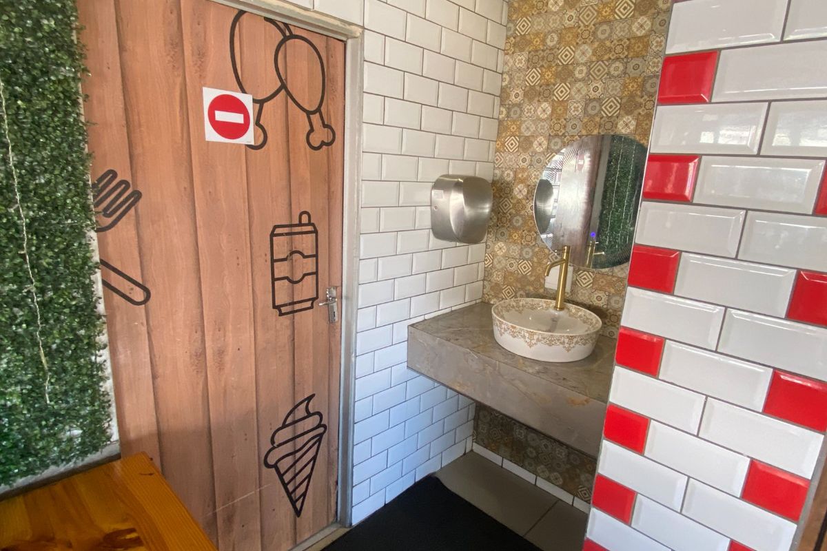 A commercial bathroom featuring a concrete vanity with a decorative vessel sink, brass faucet, and a mix of subway and patterned accent tiling.