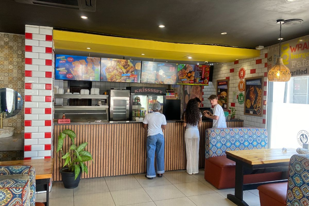 Commercial kitchen service area featuring a wood-paneled counter, tiled wall accents, and integrated menu displays for a fast-food service environment.