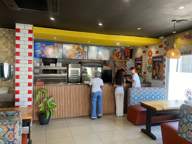Commercial kitchen service area featuring a wood-paneled counter, tiled wall accents, and integrated menu displays for a fast-food service environment.