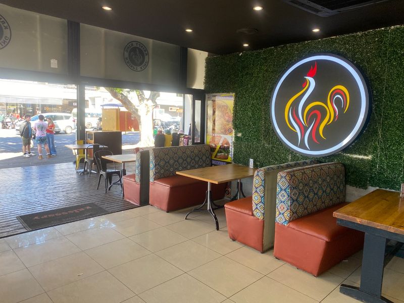 Commercial open-plan dining area featuring built-in booth seating, an artificial green wall with illuminated signage, and large sliding doors opening to an outdoor deck.