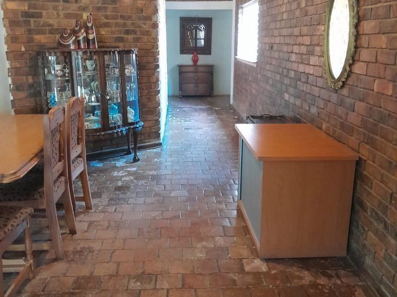 Living area featuring rustic exposed brick walls and traditional terracotta tile flooring, offering a classic, textured aesthetic with potential for modern updates.