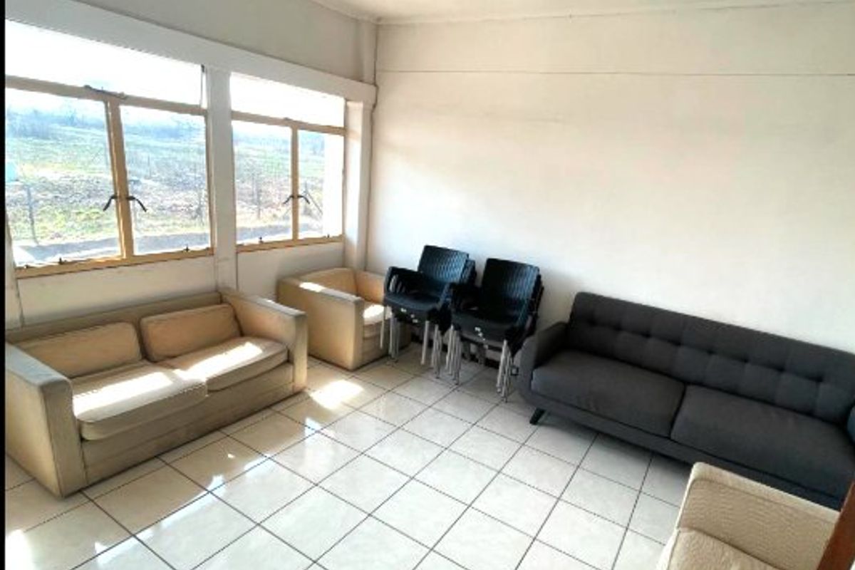 A functional commercial living area featuring large windows for natural light, tiled flooring, and a standard ceiling-mounted fluorescent light fixture.