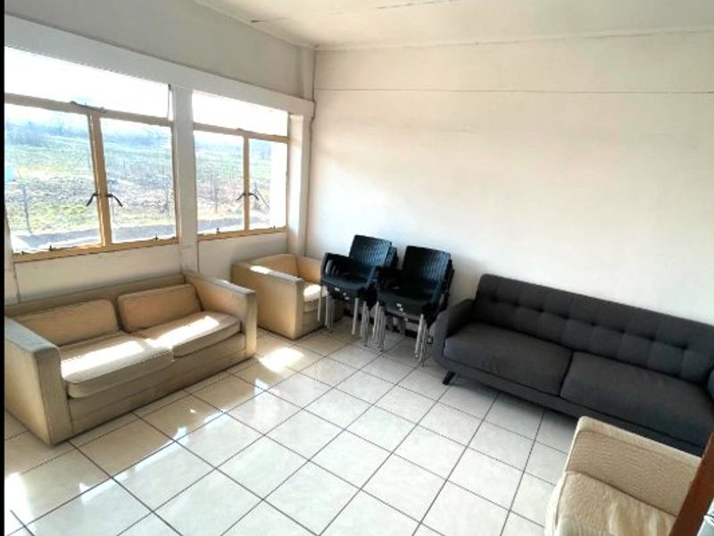 A functional commercial living area featuring large windows for natural light, tiled flooring, and a standard ceiling-mounted fluorescent light fixture.