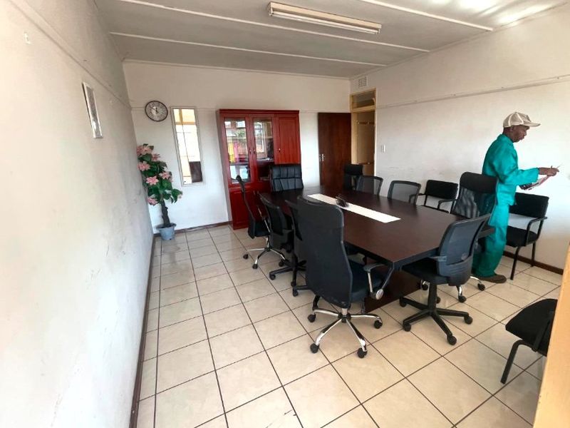 A functional office meeting room featuring ceramic tile flooring, a built-in storage cabinet, and overhead fluorescent lighting.