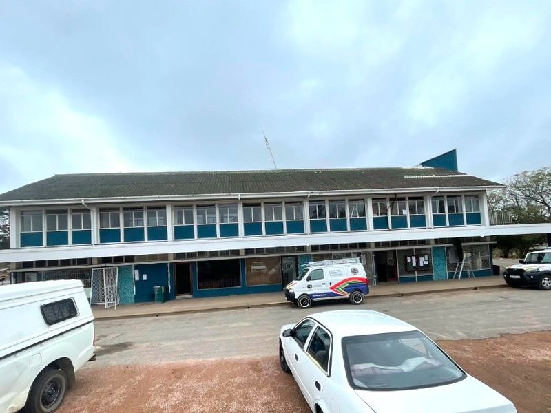 Front elevation of a commercial building featuring a multi-pane window facade, covered walkway, and tiled roof structure.
