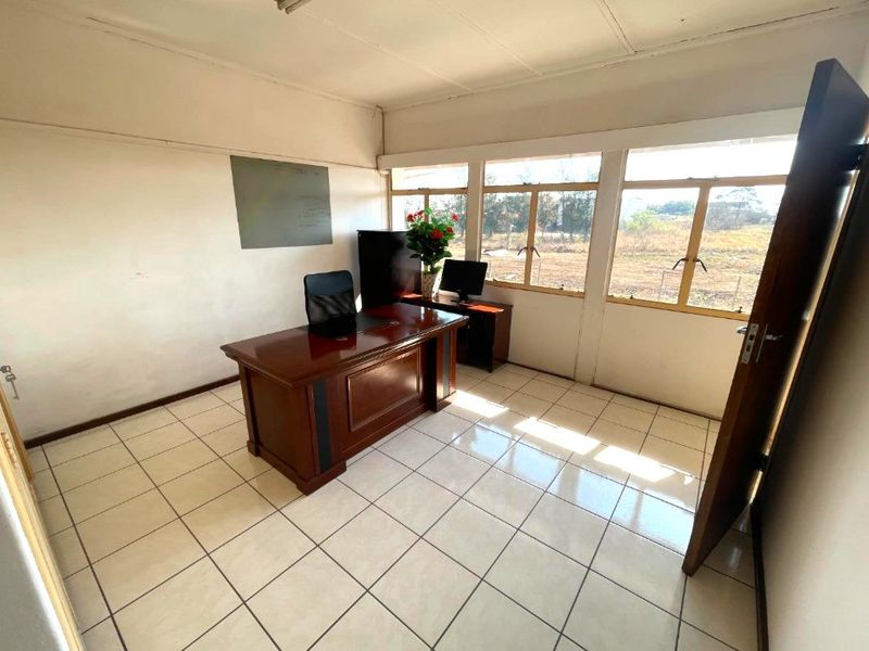 A functional office space featuring tiled flooring and large windows providing natural light, suitable for a professional commercial workspace.