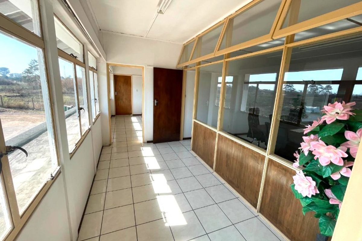 A bright, tiled commercial hallway featuring timber-framed glass partitions and access to adjacent office spaces.