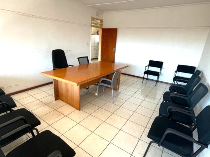 A functional office space featuring ceramic tiled flooring and fluorescent lighting, suitable for a meeting room or workspace.