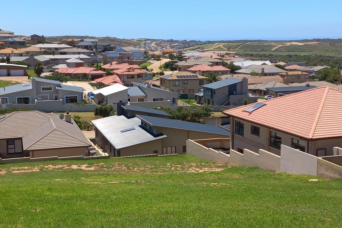 Elevated view overlooking a residential neighborhood with a sloped grass foreground and surrounding suburban housing.
