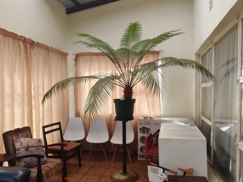 A sunroom or enclosed patio area featuring tiled flooring, large sliding glass doors, and security bars, offering a bright and functional transition space.
