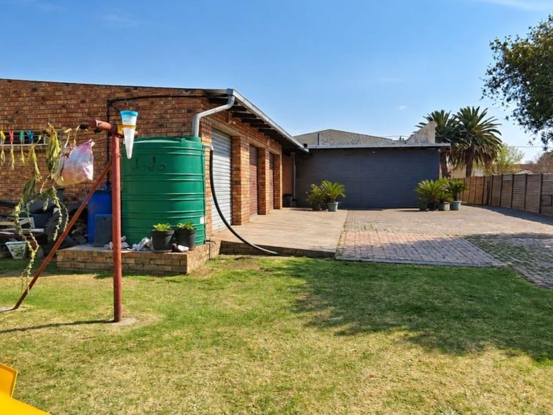Rear exterior view of the property featuring a brick facade, paved driveway, and a water tank installation.