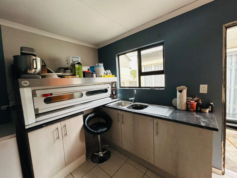 Compact scullery area featuring built-in cabinetry, a stainless steel sink, and a commercial-style oven, providing functional prep and wash-up space.