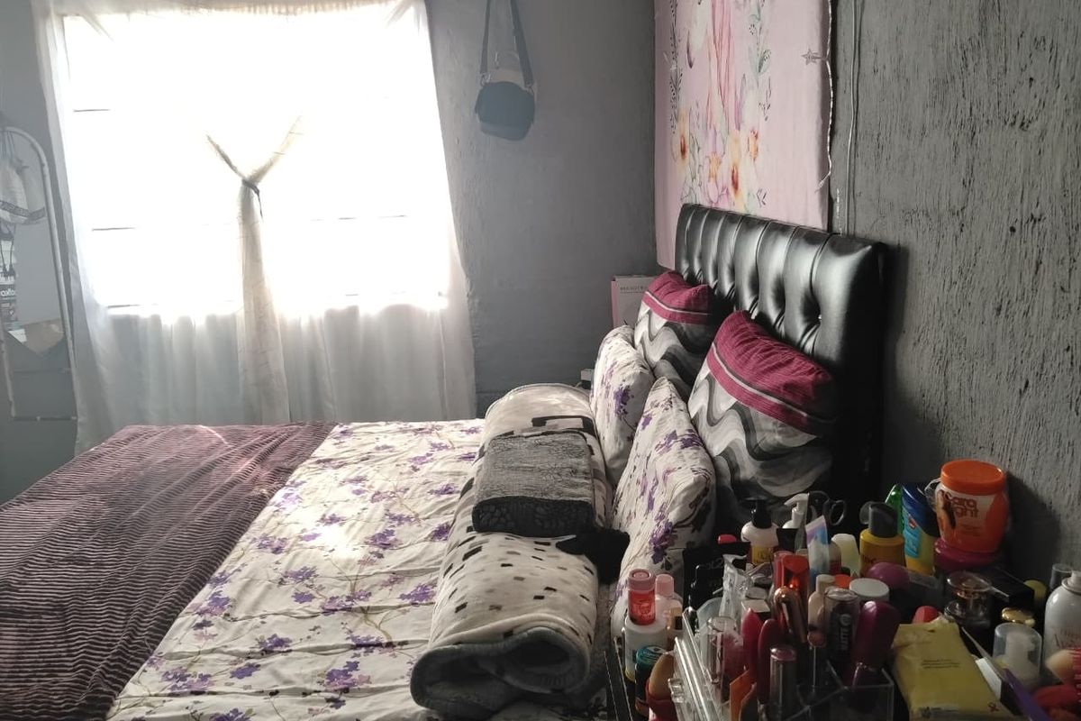 A bedroom featuring a window and textured wall finishes, requiring cosmetic updates to improve the overall aesthetic and condition of the space.