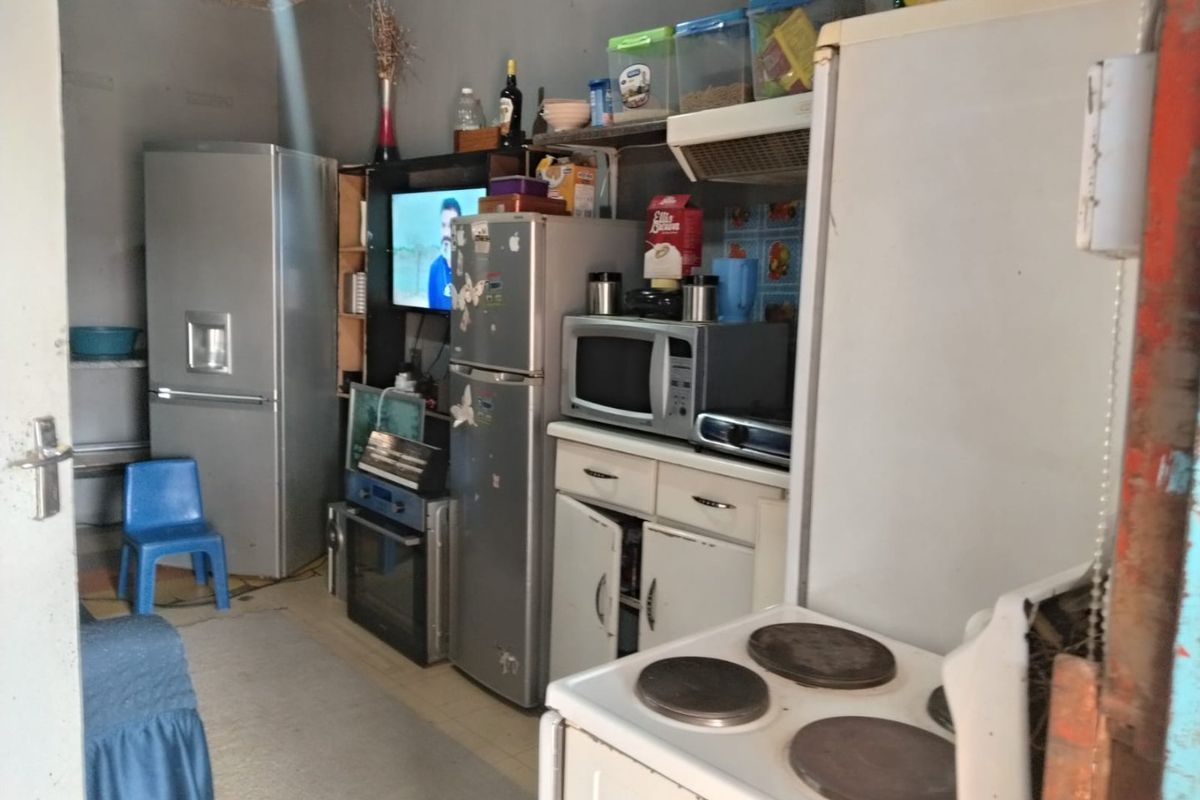 A compact kitchen area featuring basic cabinetry, an electric stove, and an extractor fan, requiring cosmetic updates to improve functionality and aesthetic appeal.